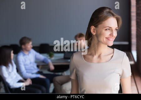 Sorridente millenario leader femmina che guarda lontano sognando il futuro Foto Stock