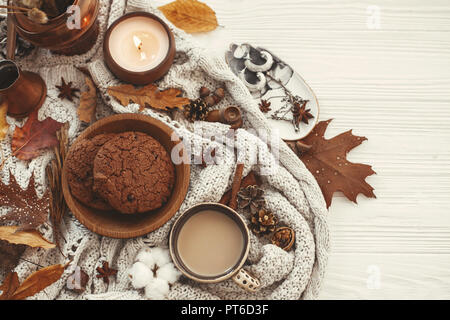 Elegante appartamento di autunno laici. Un delizioso caffè,cookie e belle foglie di autunno, candela, dadi, ghiande, cotone, cannella sul maglione e bianco backgr rustico Foto Stock