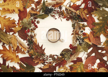 Autunno Ghirlanda laici piana. Caffè in autunno lascia il cerchio con bacche, dadi, ghiande, fiori,erbe sul rustico sfondo bianco vista dall'alto. I migliori auguri di Buon Natale. Foto Stock