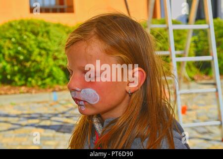 Bella ragazza giovane con la faccia dipinta come un coniglio. Volto dipinto sul volto del bambino. Foto Stock