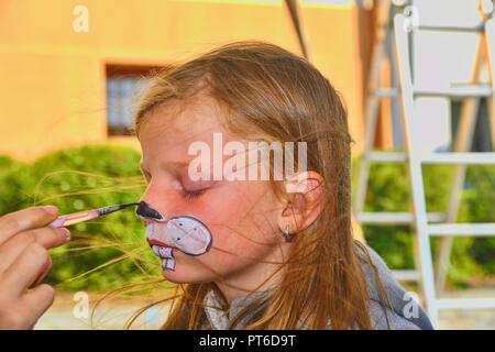 Bella ragazza giovane con la faccia dipinta come un coniglio. Volto dipinto sul volto del bambino. Foto Stock