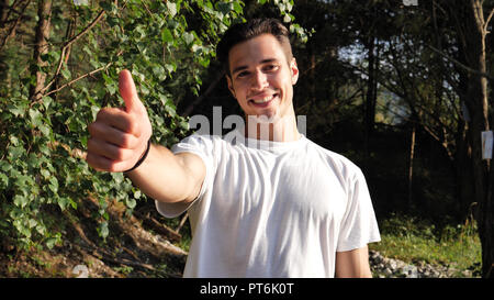 Giovane uomo nella natura facendo pollice in alto Foto Stock