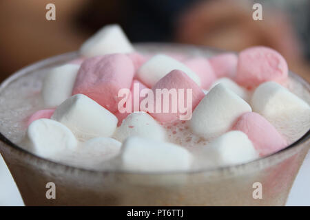 Un cioccolato caldo ripiano in vetro con rosa e bianco marshmallows. Foto Stock