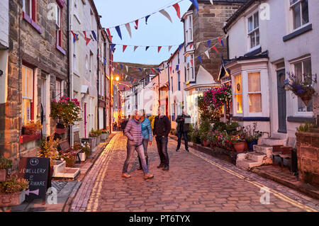 Crepuscolo in Staithes la sera dell'annuale festival delle arti, North Yorkshire east coast, nell'Inghilterra del nord, REGNO UNITO, occupato high street Foto Stock