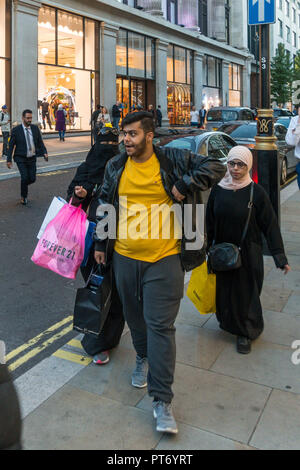Uomo musulmano e due donne con le borse della spesa a piedi verso il basso teh Street a Londra, Regno Unito, Europa. Foto Stock