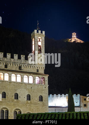 La fotografia notturna del Palazzo dei Consoli di Gubbio e in alto a destra, il monastero di Sant'Ubaldo Foto Stock