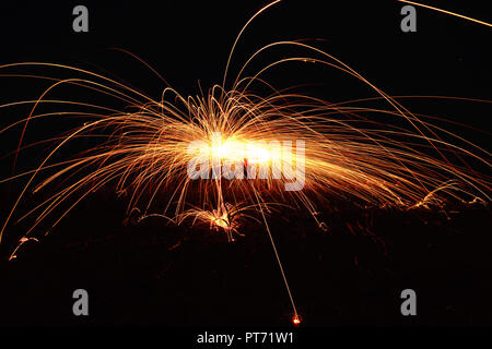 Incredibile spettacolo di fuoco durante la notte ad un festival o festa di nozze. Fire ballerini swing, filatura rosso fuoco. Foto Stock