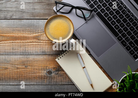 Tazza di caffè sopra il libro ed il computer portatile sulla tavola di  legno in caffè.