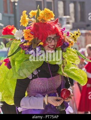 Asheville, North Carolina, Stati Uniti d'America - 7 Febbraio 2016: Felice donna che indossa un creative in maniera colorata, fiorito Mardi Gras costume sorrisi come lei cammina in un Foto Stock