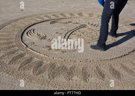 Un volontario che lavora su un grande labirinto di sabbia creato da Denny Dyke, a Heceta Beach in Firenze, Oregon, Stati Uniti d'America. Foto Stock