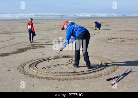 Un volontario che lavora su un grande labirinto di sabbia creato da Denny Dyke, a Heceta Beach in Firenze, Oregon, Stati Uniti d'America. Foto Stock