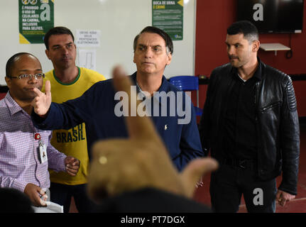 Rio de Janeiro, Brasile. 07 ott 2018. 07 ottobre 2018, Brasile, Rio de Janeiro: Jair Bolsonaro (C), ultra-candidato giusto per il posto di presidente brasiliano, parla dopo la fusione il suo voto in corrispondenza di una stazione di polling nella scuola della città Rosa da Fonseca, in Vila Militar, a ovest della città. In fondo è il suo figlio Flavio Bolsonaro (2-L). Nel mezzo di una grave crisi, l'elezione presidenziale ha avviato in Brasile. Credito: Fabio Teixeira/dpa/Alamy Live News Foto Stock