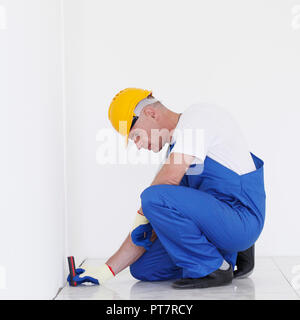 Il lavoratore fa opere di finitura delle pareti utilizzando una linea laser livello. Laser dispositivo di roulette Foto Stock