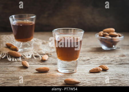 Liquore italiano Amaretto con mandorle in legno rustico sfondo, spazio di copia Foto Stock