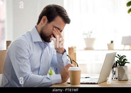 Stanco lavoratore seduto alla scrivania in ufficio Foto Stock