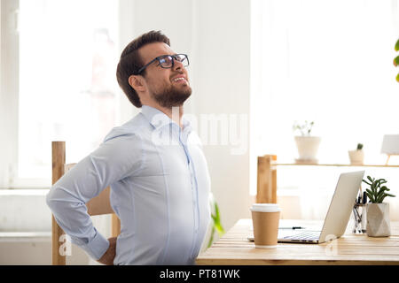 Imprenditore seduto in ufficio ha un mal di schiena Foto Stock