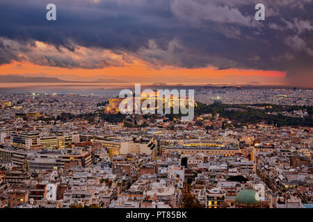 Illuminata Acropoli di Atene in Grecia al cielo nuvoloso tramonto con il mare e le montagne sullo sfondo Foto Stock