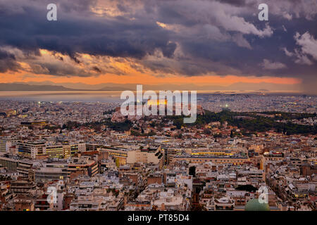 Illuminata Acropoli di Atene in Grecia al cielo nuvoloso tramonto con il mare e le montagne sullo sfondo Foto Stock