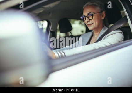 Coppia imprenditrice concentrando sulla strada durante la guida di un'auto. Senior imprenditore femmina viaggia per lavoro nella sua auto. Foto Stock