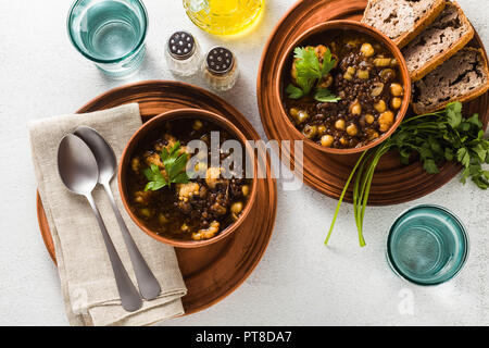 Nero marocchino, zuppa di lenticchie e ceci con cavolfiore in ciotole sul tavolo. vegano sano comfort food con pane integrale Foto Stock