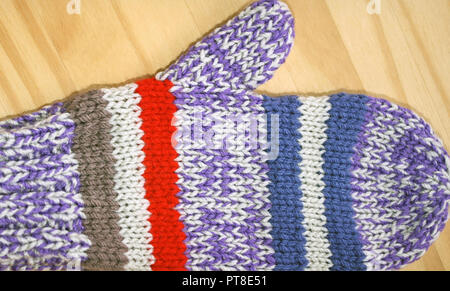 Luminose e colorate a mano a maglia mitten in rosso, viola, blu e bianche Foto Stock