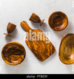 Utensili di legno di ulivo sul bianco tavolo da cucina e i rami di ulivo. eco-friendly kitchenware Foto Stock