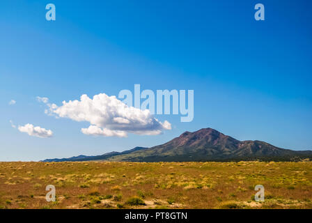 Nel deserto dello Utah occidentale, questo piccolo picco aumenta bruscamente da vasti campi di salvia ed erbe in arido paesaggio. Al di sopra di una piccola forma di cloud Foto Stock