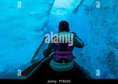 Pagaiando una canoa tra il blu cristallino pareti di una caverna di ghiaccio vicino alla superficie del lago con terminazione ghiacciaio Valdez in Alaska Foto Stock