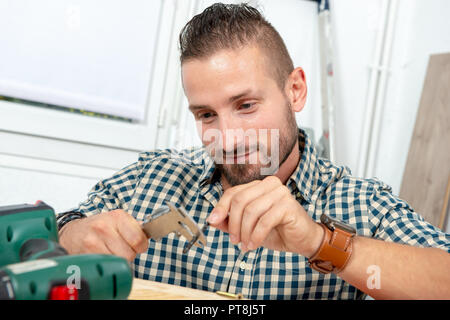 Un giovane uomo di punta di misurazione utilizzando la pinza Foto Stock