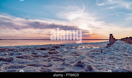 Bel tramonto o l'alba su un lago salato in legno, canapa nell'accumulo di sale dopo la essiccazione del lago. Foto Stock