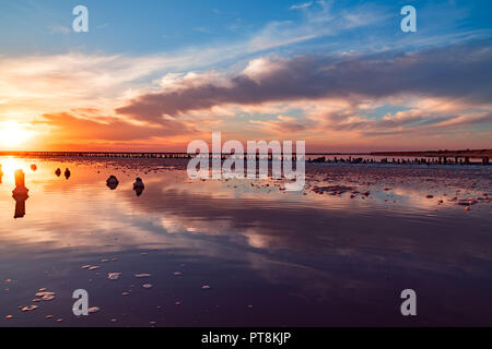 Bel tramonto o l'alba su un lago salato in legno, canapa nell'accumulo di sale dopo la essiccazione del lago. Foto Stock