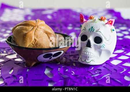 Il giorno dei morti altare, con zucchero cranio, pane tradizionale e viola papel picado. Foto Stock