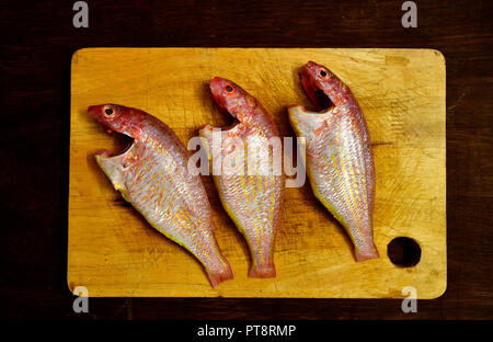 Concetto di frutti di mare. Tagliere in colore giallo con Rosa pesce persico e il coltello. Pulire Rosa Pesce persico bistecche con il coltello sul tagliere. Foto Stock