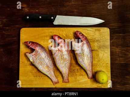 Concetto di frutti di mare. Tagliere in colore giallo con Rosa pesce persico e il coltello. Pulire Rosa Pesce persico bistecche con il coltello sul tagliere. Foto Stock