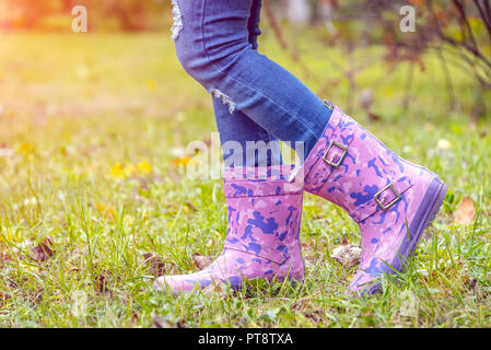 Bambini i piedi in stivali di gomma su ingiallito erba secca in autunno Foto Stock