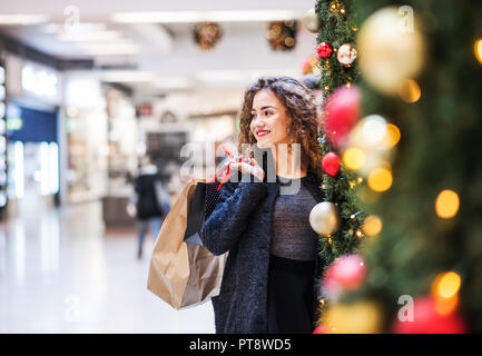 Un Ritratto di ragazza adolescente con sacchetti di carta in centro per lo shopping di Natale. Foto Stock
