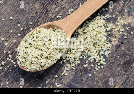 Pelate organici sementi di canapa in un cucchiaio su tavola in legno rustico. Mangiare sano supplemento. Super concetto. Foto Stock