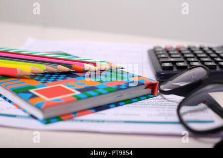 Foto di forma, taccuino, matita colorata, calcolatrice e bicchieri. Foto Stock