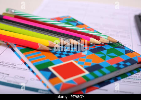 Immagine del modulo, notebook e matita colorata. Isolato su sfondo di legno. Foto Stock