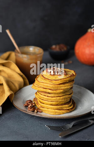 Pila di gustose frittelle di zucca con le noci pecan e salsa al caramello. Messa a fuoco selettiva Foto Stock