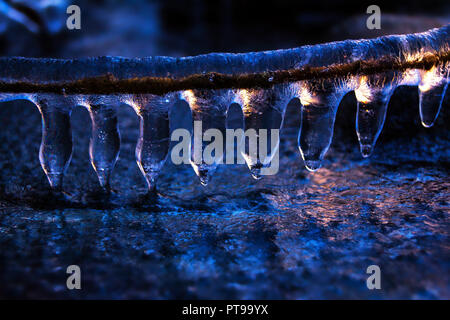 Icycles colorati - la luce del tramonto e colori riflessi dall'acqua gelata. Foto Stock