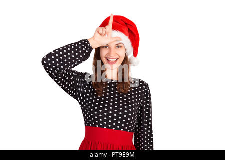 Ritratto di giocosa donna pazzesca nel vestire tenendo la mano che mostra la lettera L rendendo gesto perdente e sorridente. ragazza emotiva in santa claus cappello di Natale ho Foto Stock