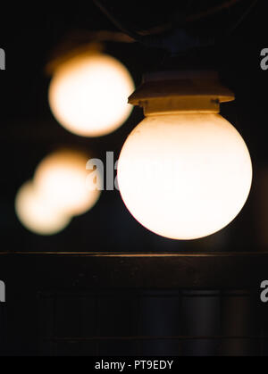 Una serie di 4 lampadine in una linea su sfondo scuro Foto Stock