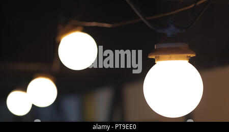 Una serie di 4 lampadine in una linea su sfondo scuro Foto Stock