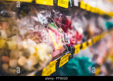 Gustosa cercando di rosso e di giallo i dolciumi e caramelle in un involucro su uno scaffale di un negozio di dolci Matlock, Regno Unito Foto Stock