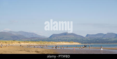 Paesaggio panoramico: Famiglie sulla spiaggia di Newborough Warren, Anglesey, Snowdonia montagna sfondo. Soggiorno estivo per turisti britannici. Foto Stock