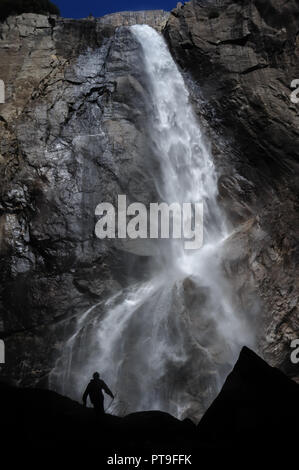 Silhoutte di un escursionista che passa nella parte anteriore della parte inferiore della Yosemite Falls. Parco Nazionale di Yosemite, ca. Foto Stock