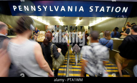 Un movimento sfocato dei pendolari che scendono nelle viscere di Penn Station durante l'ora di punta serale quotidiana a New York, New York. Foto Stock