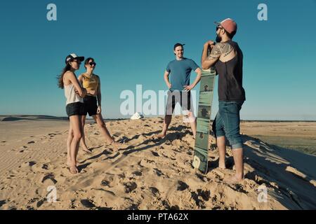 Santa Cruz, Bolivia - Settembre 5 2018: giovani donna e uomo sand boarding al dune di sabbia del deserto vicino alla città Foto Stock