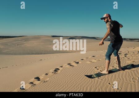 Santa Cruz, Bolivia - Settembre 5 2018: giovane sand boarding al dune di sabbia del deserto vicino alla città Foto Stock